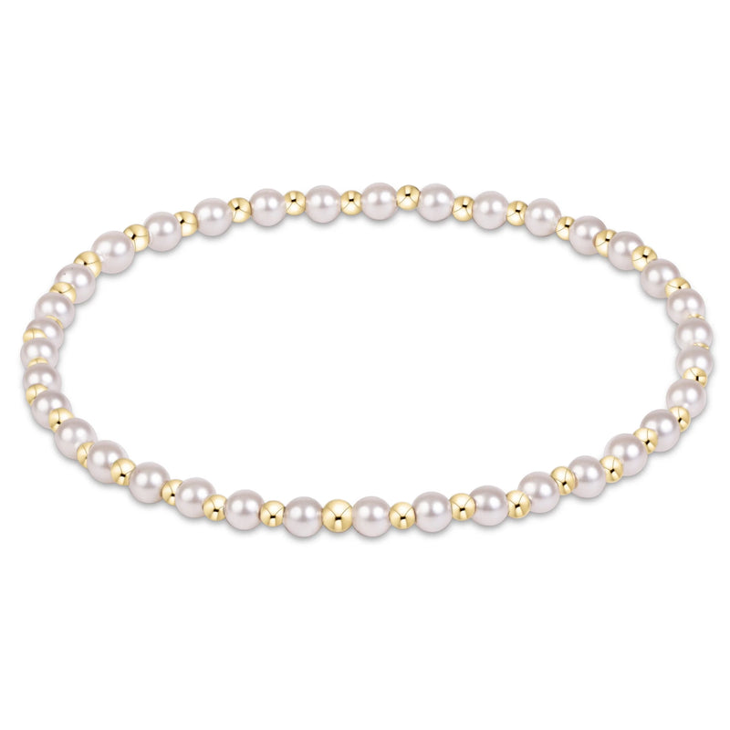 A beaded stretch bracelet featuring white freshwater pearls and polished gold-tone beads, arranged in a horizontal oval on a clean white background.