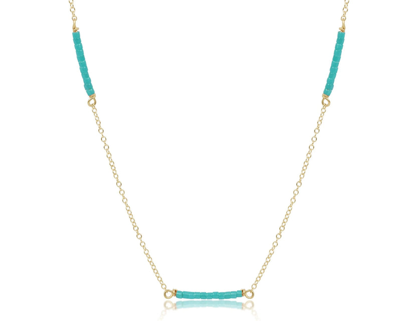 Necklace with turquoise beads on a gold chain against a white background