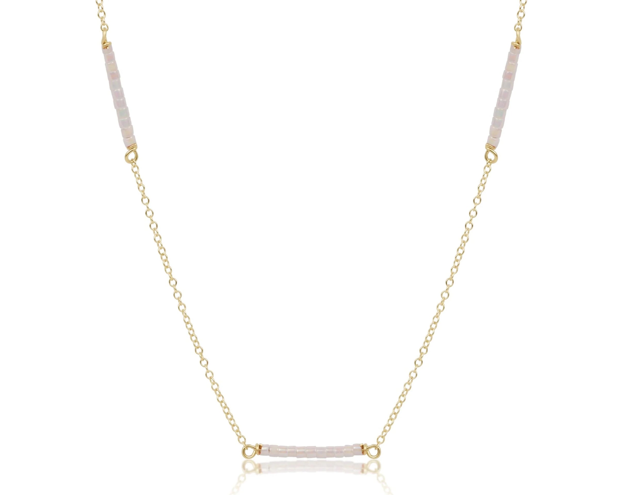 Gold necklace with pink gemstones on a white background