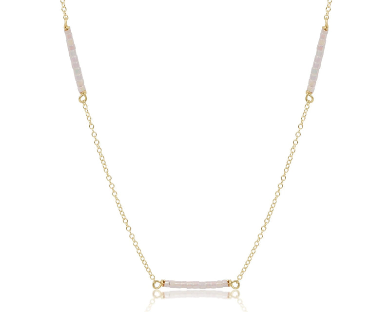 Gold necklace with pink gemstones on a white background