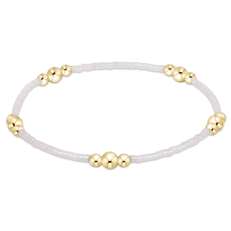White bracelet with gold beads on a white background