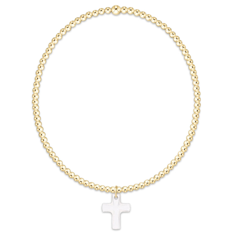 Gold beaded bracelet with a white cross pendant on a white background