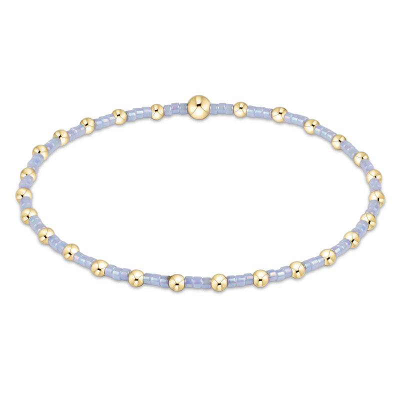 enewton Bracelet with gold beads on a light blue string against a white background