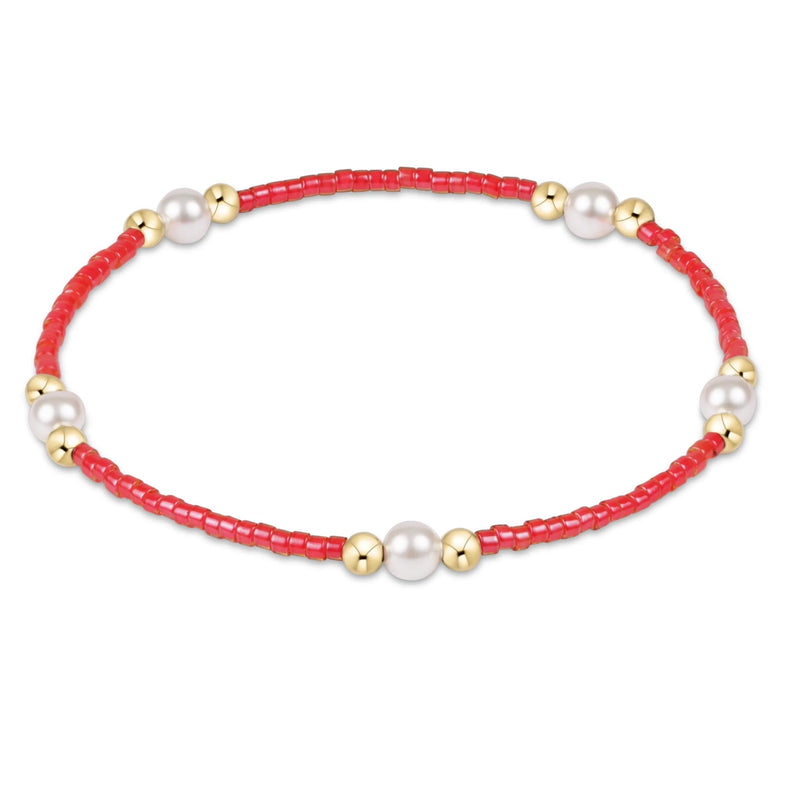 Bracelet with red beads, gold accents, and pearls on a white background