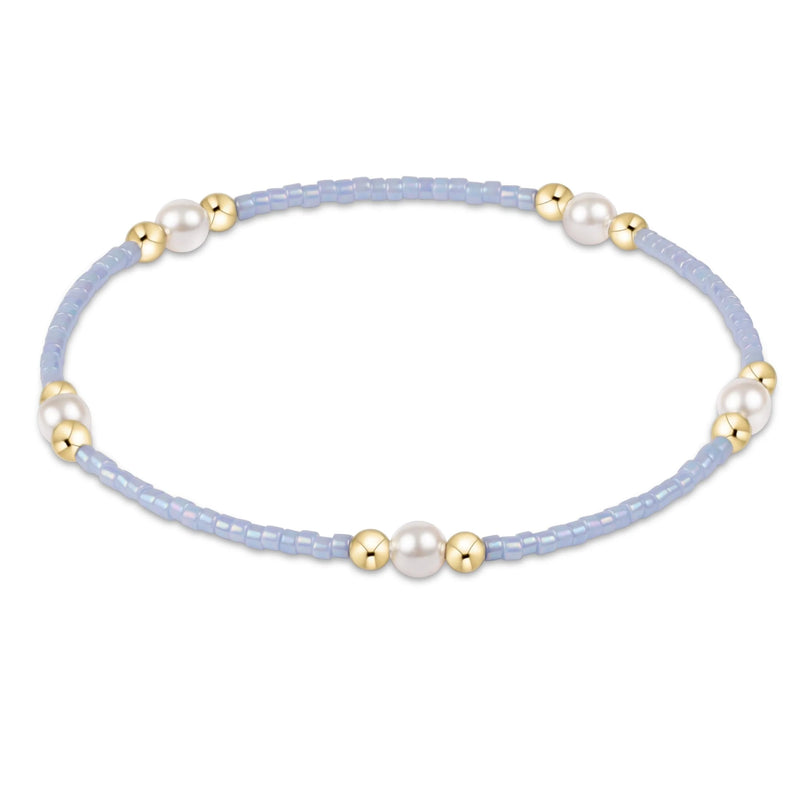 Bracelet with light blue beads, gold accents, and pearls on a white background