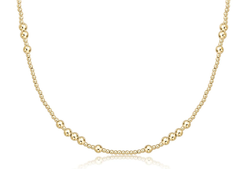 Gold beaded necklace with small gold beads and larger beads in a pattern