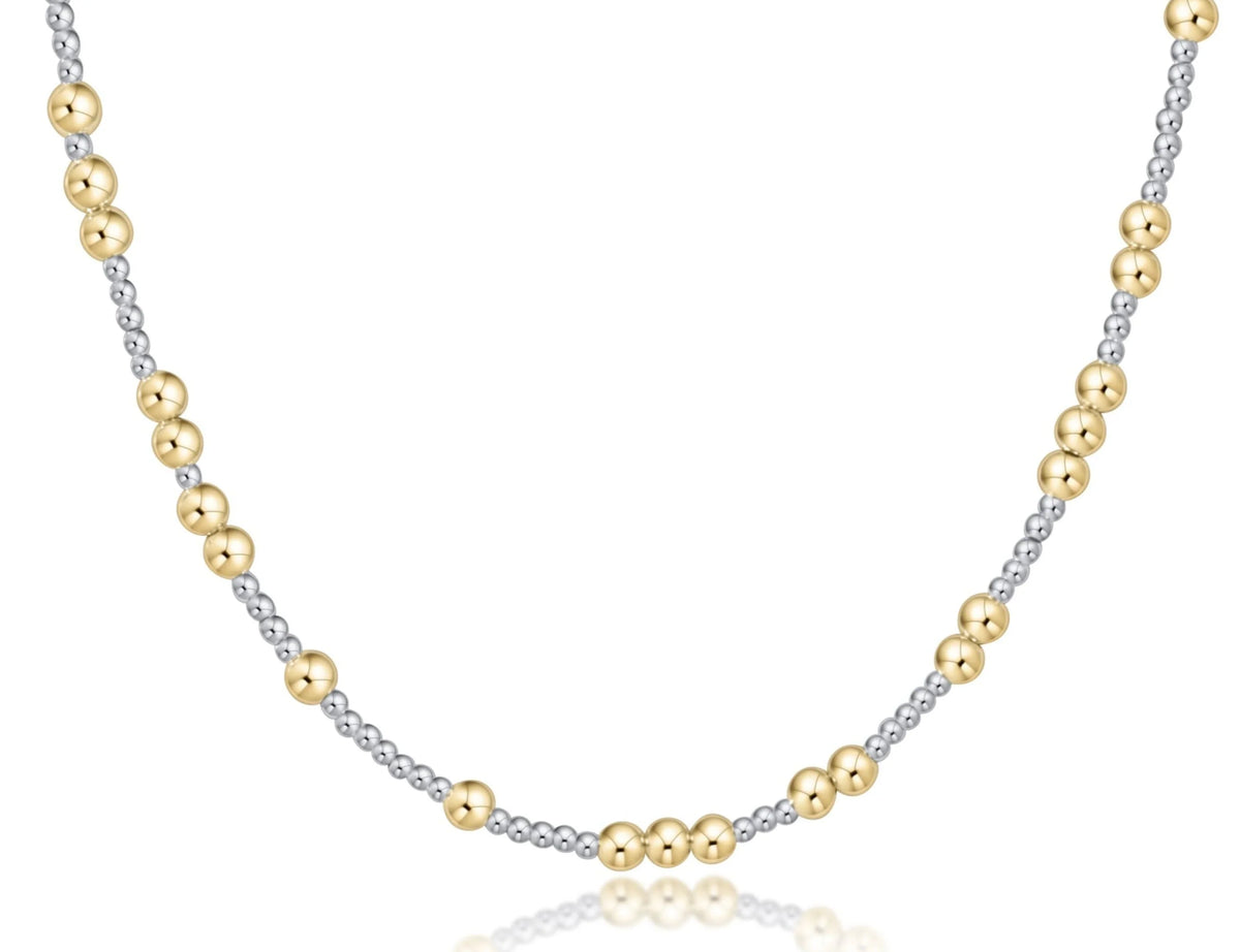 A delicate two-tone beaded necklace featuring alternating polished yellow gold and silver-toned beads, displayed on a clean white background with a subtle reflection.