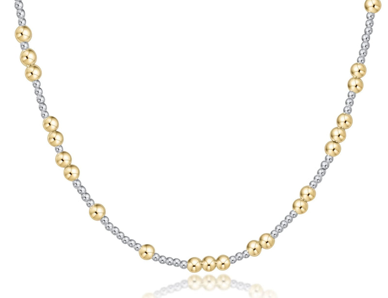 A delicate two-tone beaded necklace featuring alternating polished yellow gold and silver-toned beads, displayed on a clean white background with a subtle reflection.