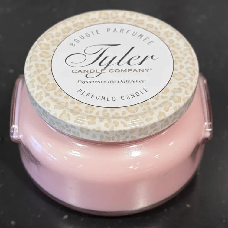 Pink candle with a decorative label on a black background