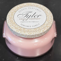Pink candle with a decorative label on a black background