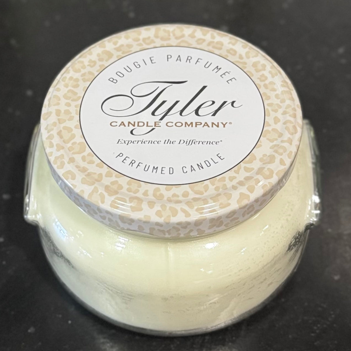 Tyler Candle Company candle with patterned lid on a dark surface