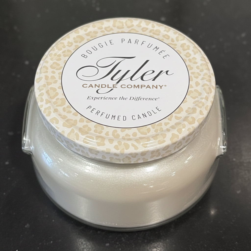 Grey candle with a decorative lid on a dark surface