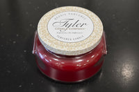 Tyler candle in a red container on a dark surface