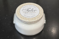 White candle with a decorative lid on a dark surface