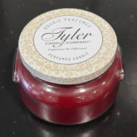 Red candle with a patterned lid featuring 'Tyler Candle Company' on a dark background