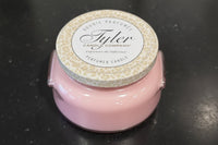 Pink candle with a white lid featuring 'Tyler Candle Company' on a black surface.