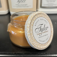 Tyler candle in a glass jar with a decorative lid on a dark surface