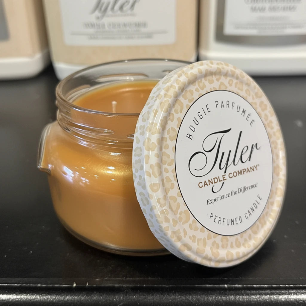 Tyler candle in a glass jar with a decorative lid on a dark surface