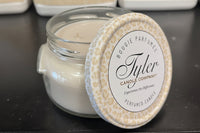 Tyler candle in a glass jar with a decorative lid on a dark surface