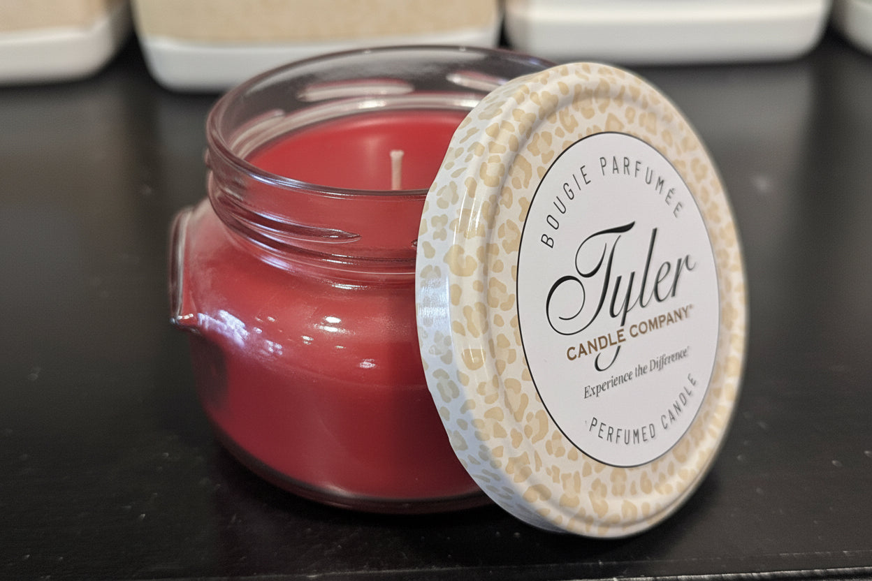 Red Candle in a glass jar with a decorative lid on a black surface, featuring the Tyler Candle Company branding.