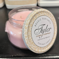 Pink candle in a clear jar with a patterned lid, featuring the Tyler Candle Company branding.