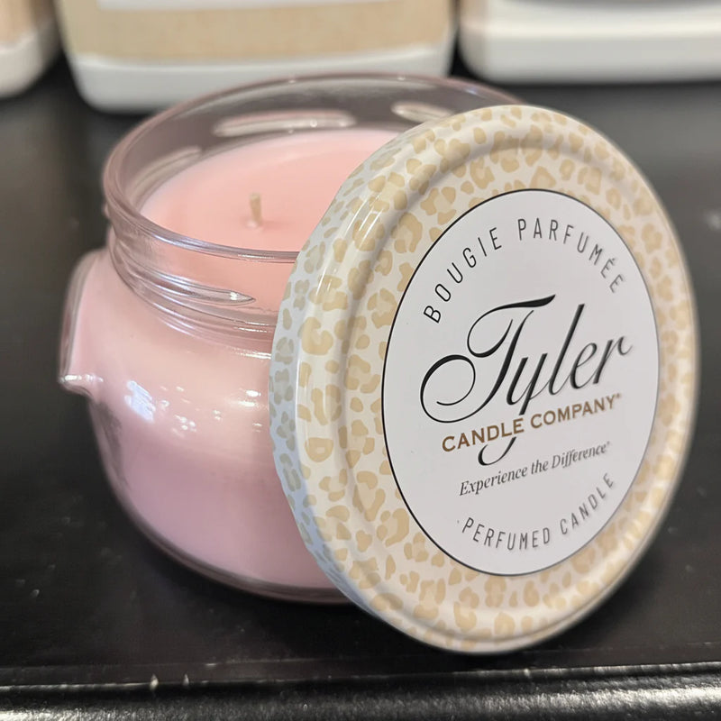 Pink candle in a clear jar with a patterned lid, featuring the Tyler Candle Company branding.