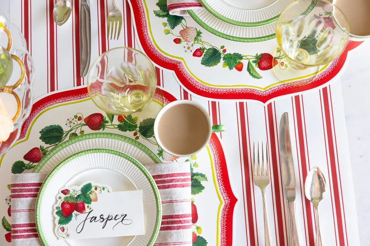 Decorative table setting with strawberry-themed plates and striped tablecloth.