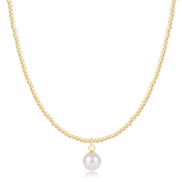 A delicate gold chain necklace featuring a single white freshwater pearl pendant, displayed against a solid white background.

