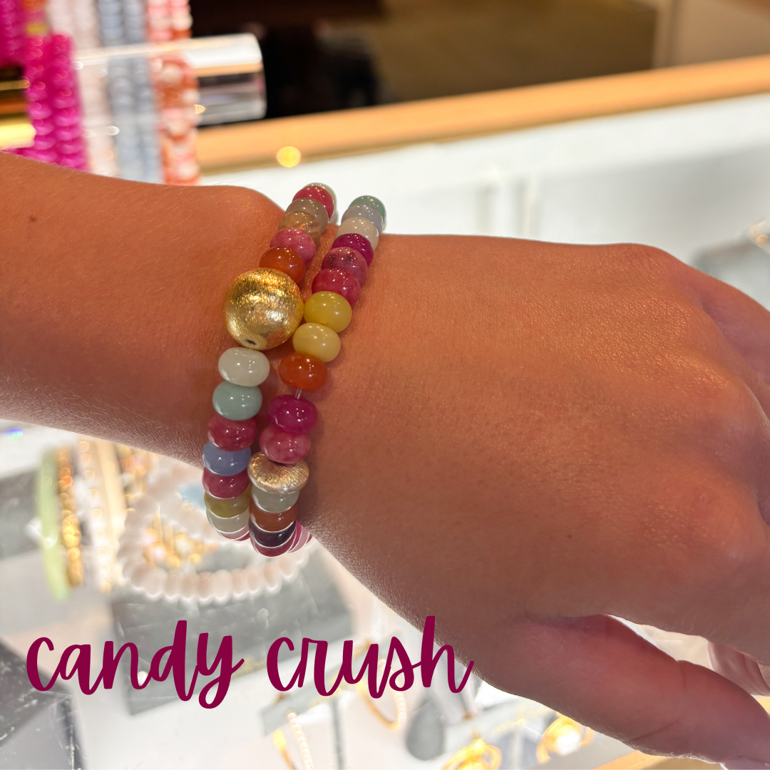 Colorful beaded bracelets on a wrist with 'candy crush' text.