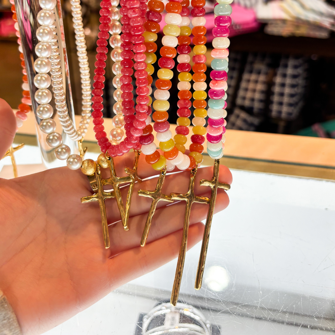 Hand holding colorful beaded bracelets on a clear stand with blurred background