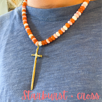 Necklace with a starburst cross pendant on a blue shirt, with 'Starburst Cross' text at the bottom.