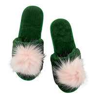 A pair of dark green plush slip-on slippers with large fluffy pale pink faux-fur pom-poms on the front, shown on a plain white background.