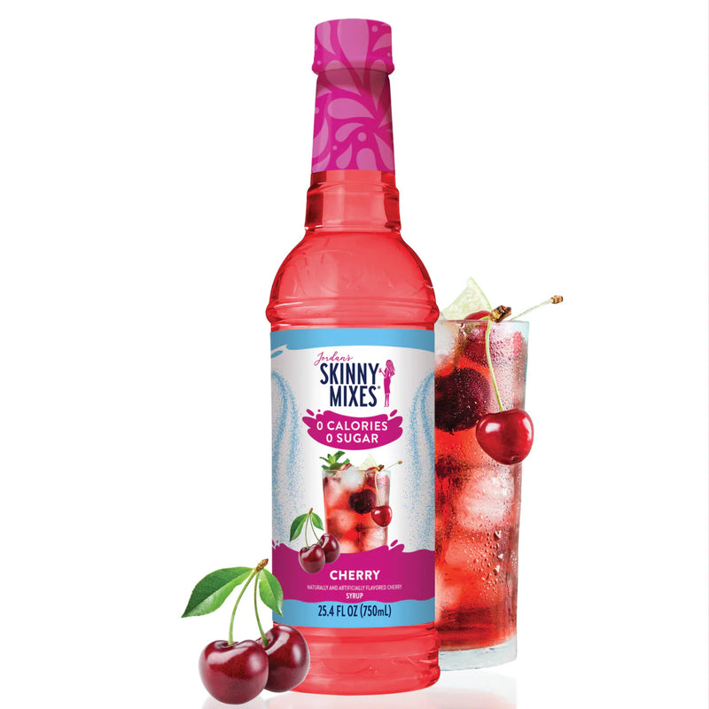 Skinny Mixes cherry syrup bottle with a glass of cherry-themed drink and cherries on a white background
