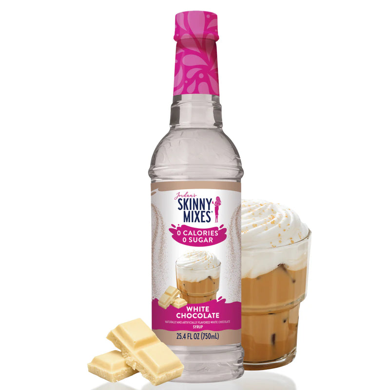 Skinny Mixes white chocolate syrup bottle with a glass of dessert and white chocolate pieces on a white background
