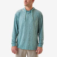 Man wearing a teal patterned long-sleeve shirt on a white background