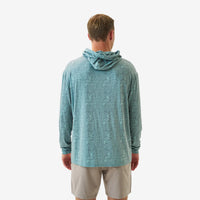 Man wearing a teal patterned hoodie and beige shorts on a white background