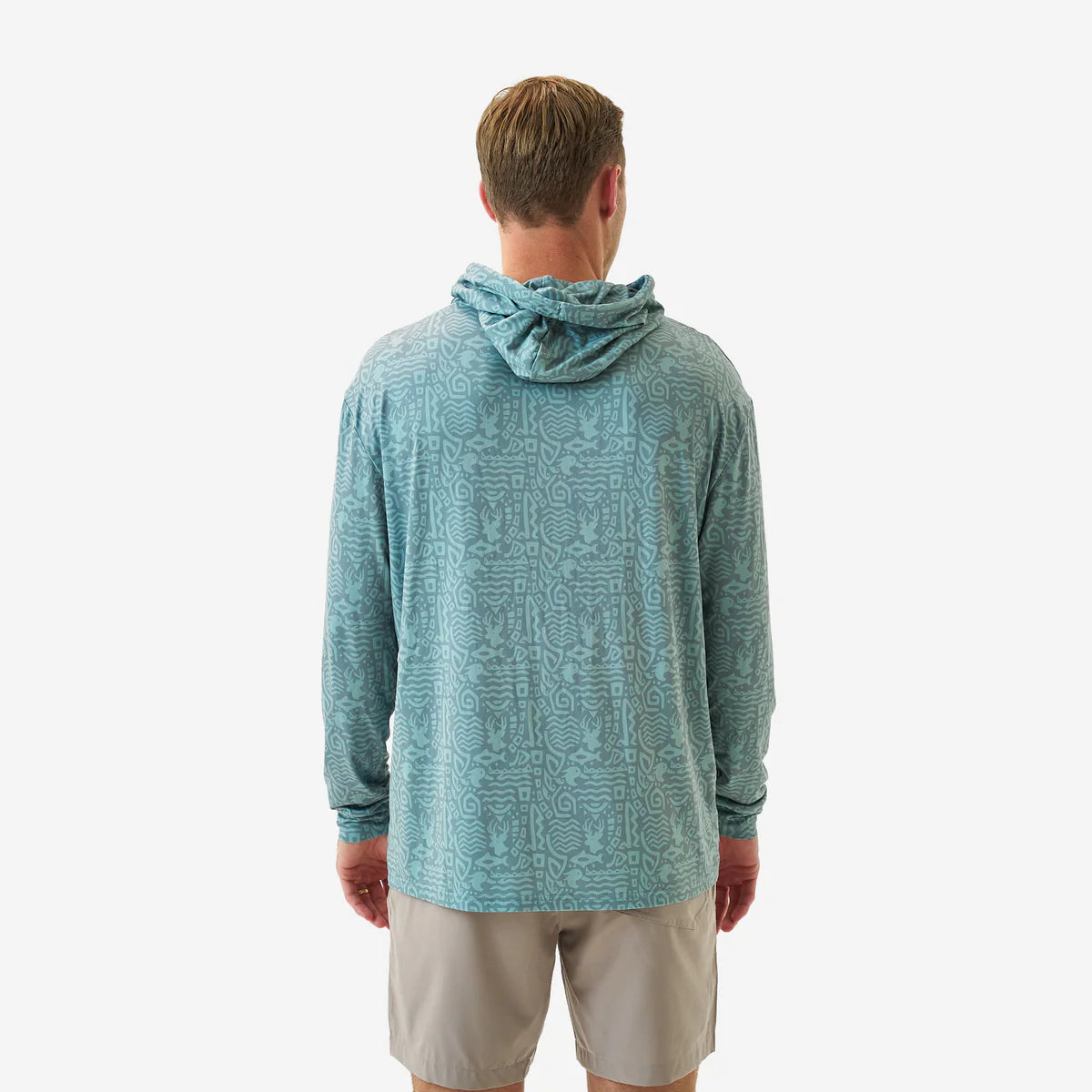 Man wearing a teal patterned hoodie and beige shorts on a white background