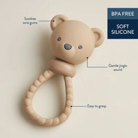 A beige silicone baby teether shaped like a teddy bear head with a textured ring handle, shown on a plain beige background.