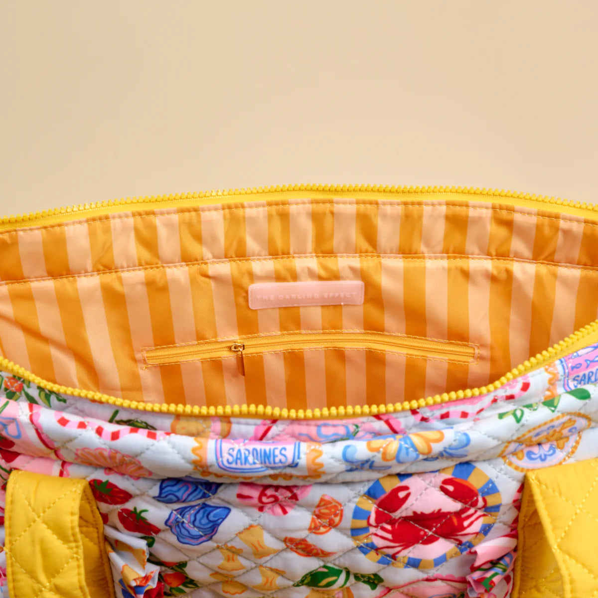 Close-up of a colorful fabric pouch with a visible brand label on a beige background
