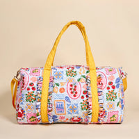Colorful patterned duffel bag with yellow handles on a beige background