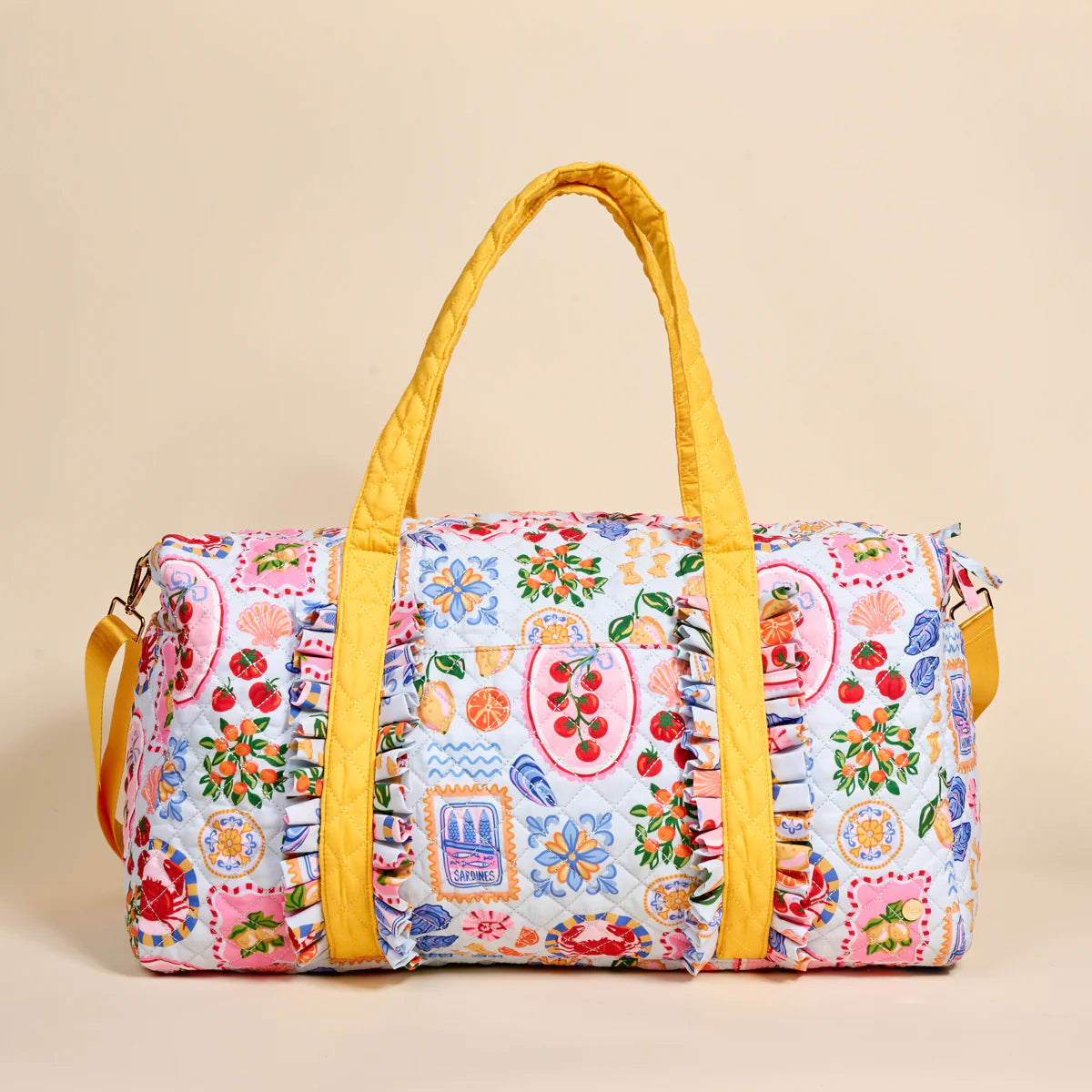Colorful patterned duffel bag with yellow handles on a beige background