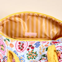 Colorful fabric pouch with floral pattern and yellow zipper on a beige background