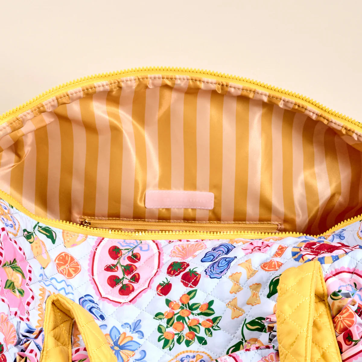 Colorful fabric pouch with floral pattern and yellow zipper on a beige background