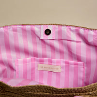 Pink and white striped bag with a brand label on a beige background