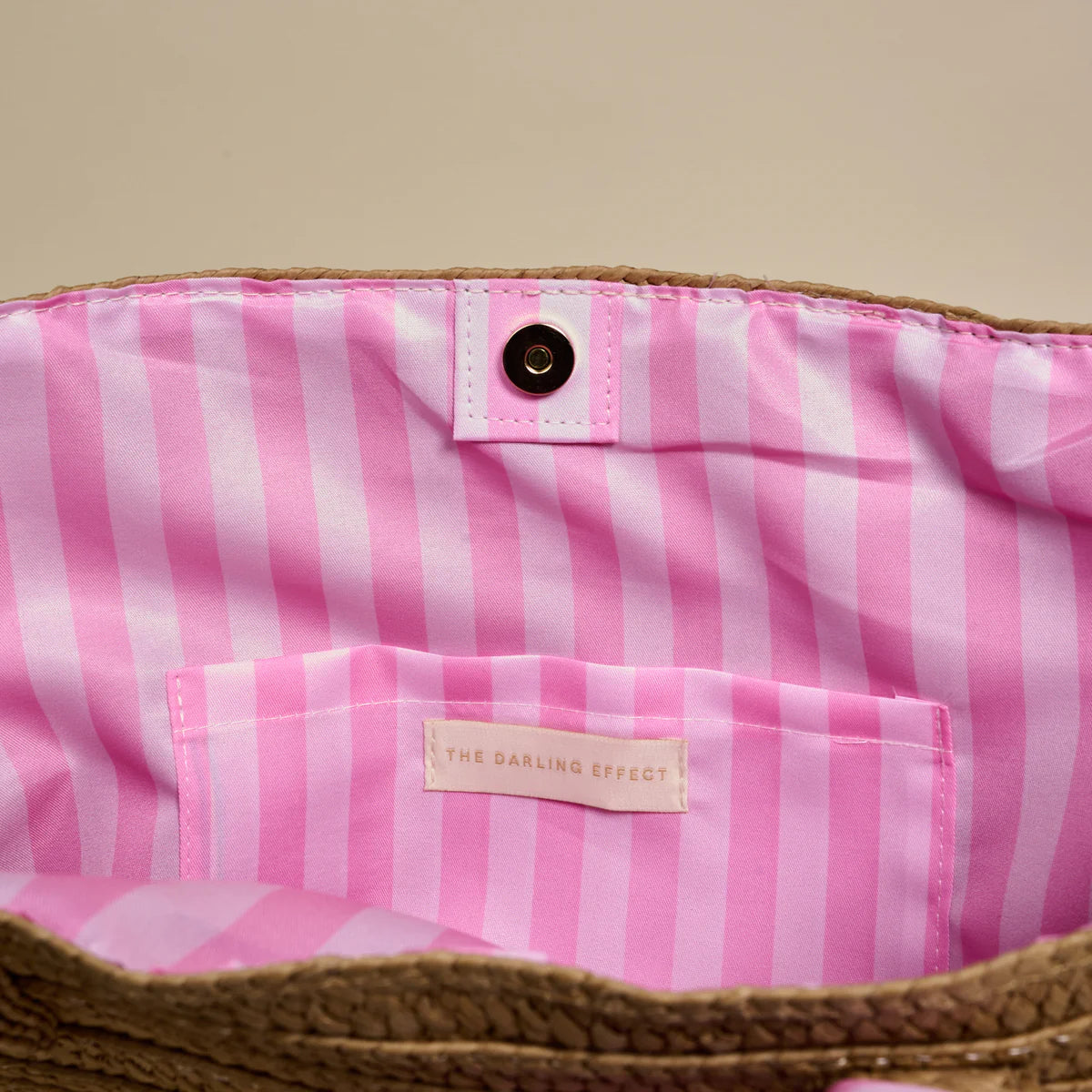Pink and white striped bag with a brand label on a beige background
