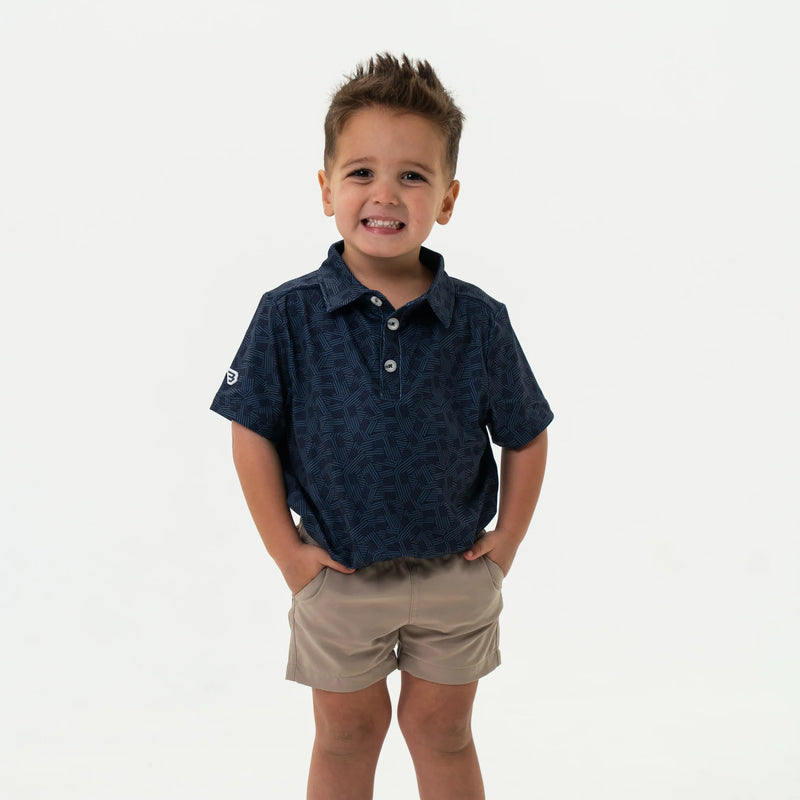 Child wearing a navy patterned shirt and beige shorts on a white background