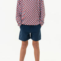 Person wearing a colorful geometric patterned shirt and navy shorts on a white background