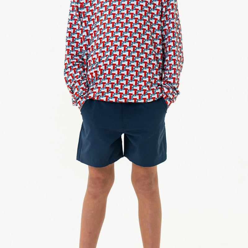 Person wearing a colorful geometric patterned shirt and navy shorts on a white background