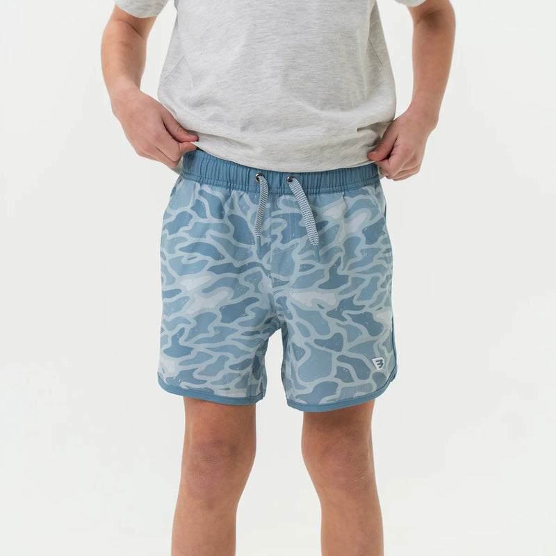 Child wearing blue camouflage shorts on a white background