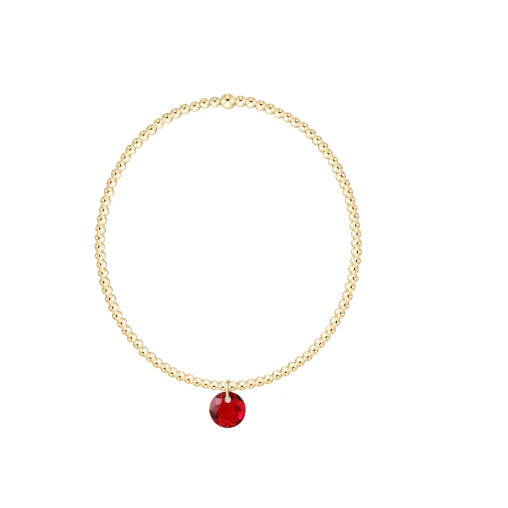 Gold bracelet with a red gemstone on a white background